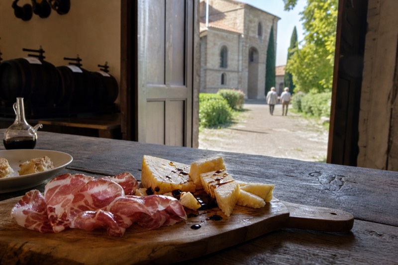 A board of cured meats and three ages of Parmigiano drizzled with balsamic on a rough table near Nonantola