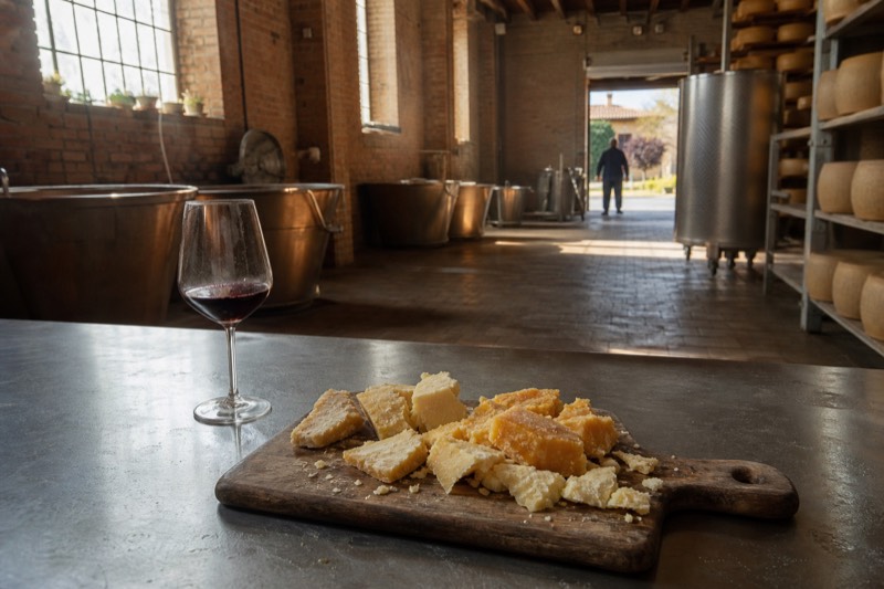 Parmigiano Reggiano shards from pale gold to deep amber on a board with Lambrusco in a dairy outside Modena