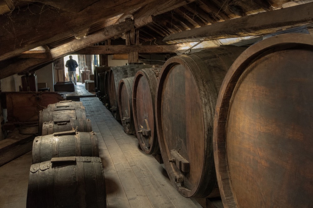 A row of ageing balsamic barrels in a traditional Modena acetaia, wooden casks of different sizes
