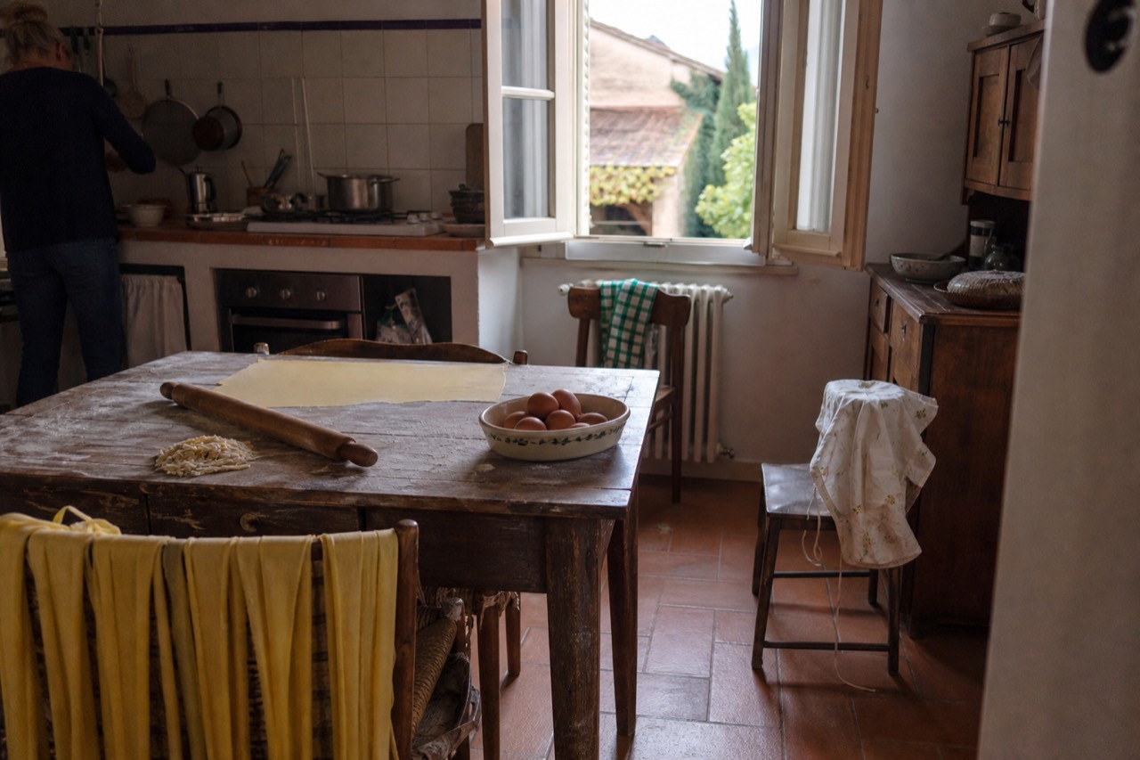 A home kitchen in Modena with a wooden table set for pasta making, ingredients and flour scattered