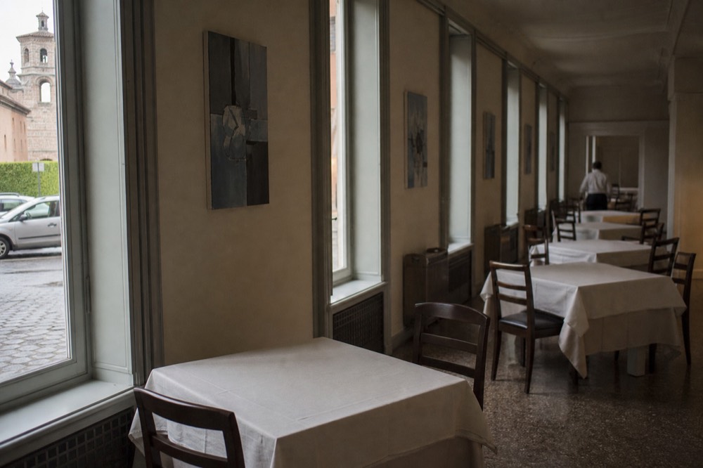 A quiet dining room with contemporary art on the walls and tables set for service