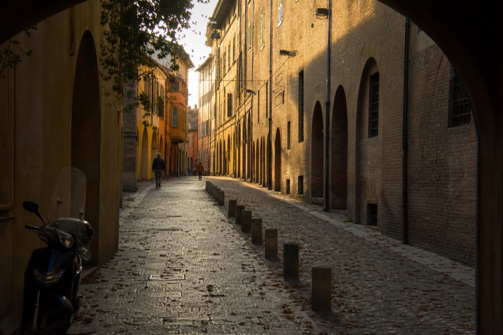 A narrow Modena street with warm evening light on old brick facades