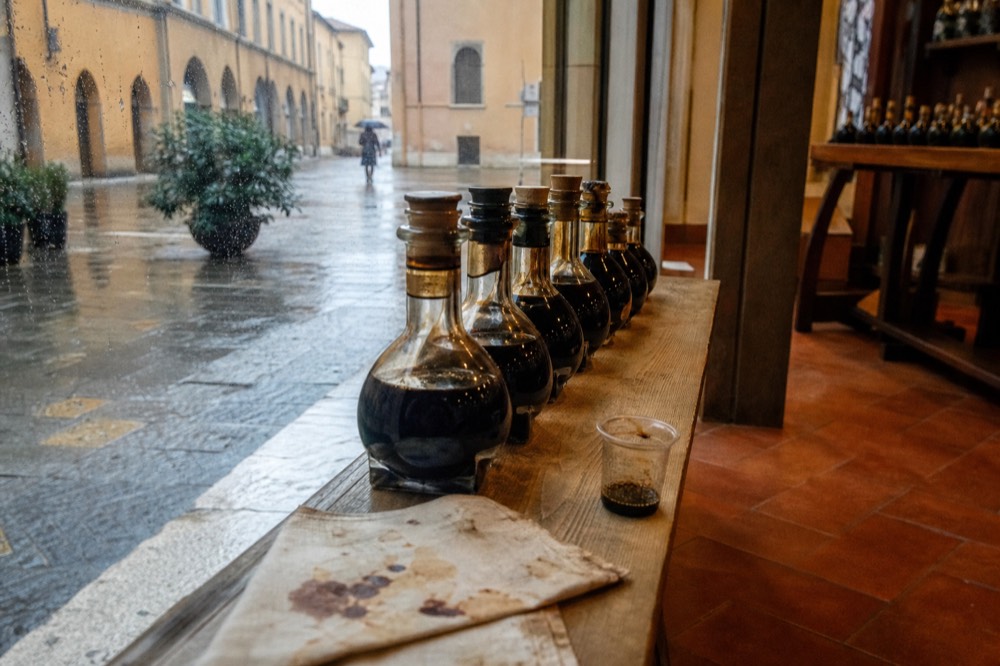 A row of labelled balsamic vinegar bottles on a wooden tasting counter