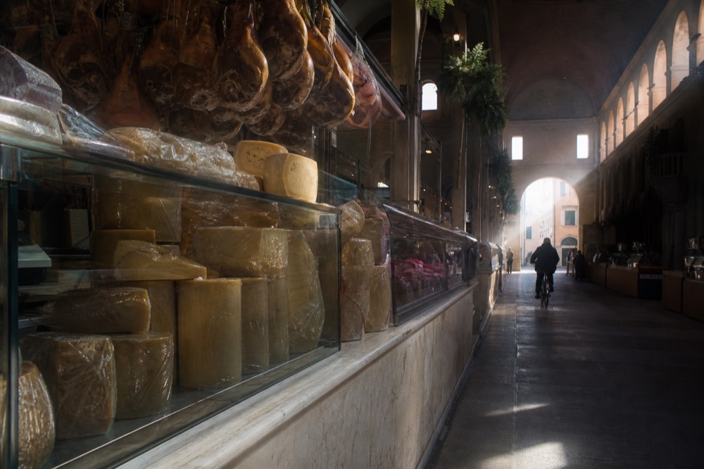 A marble counter with hanging cured hams and wheels of aged cheese in a delicatessen