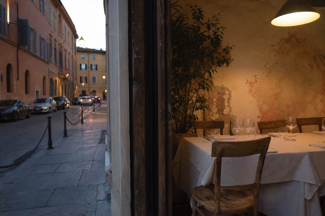 A set table with white linen and wine glasses in a warmly lit Modena dining room