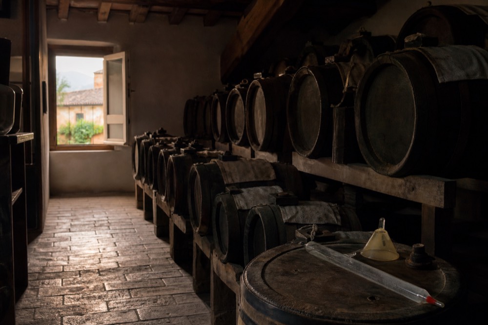 Rows of small wooden ageing barrels in a dim vinegar loft