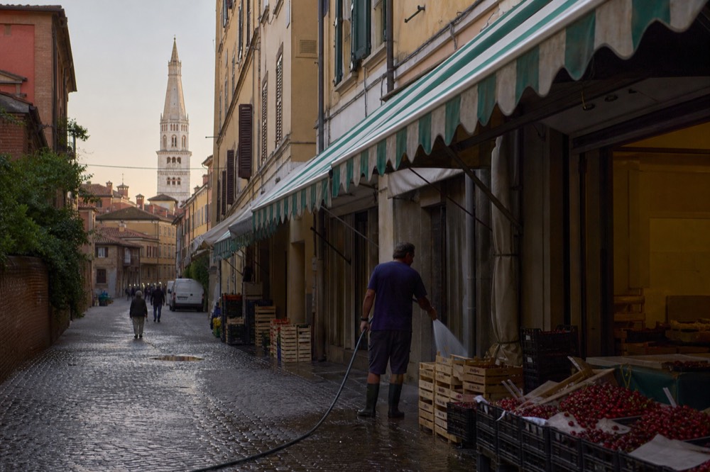 A market street with striped awnings and bicycles parked outside small shops
