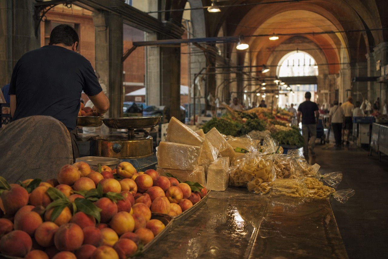 A covered market hall in Modena with produce stalls under an arched ceiling