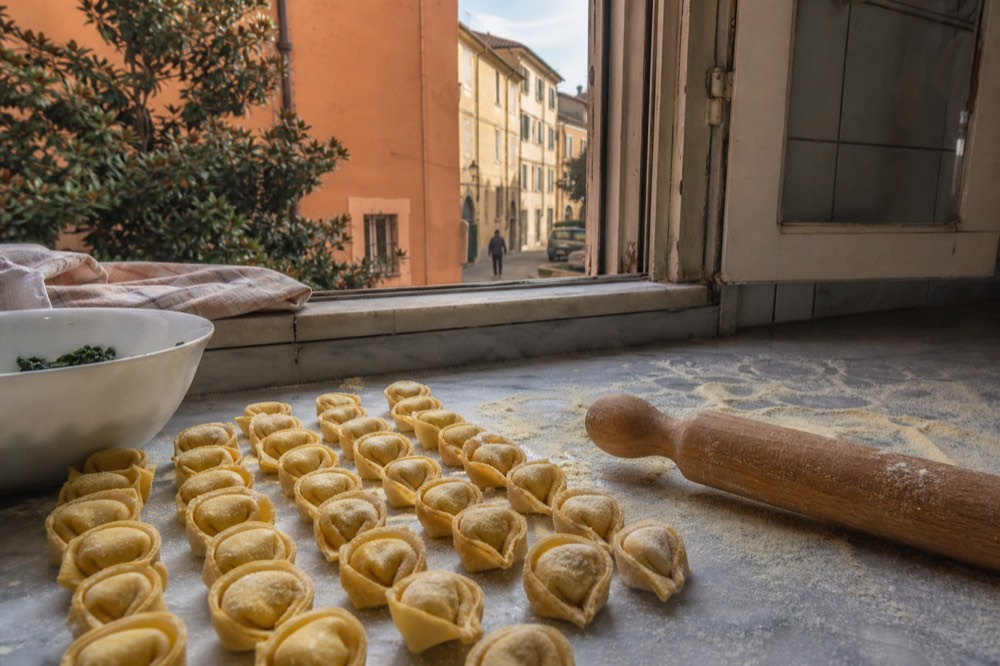 Fresh tortellini pasta arranged in rows on a marble work surface