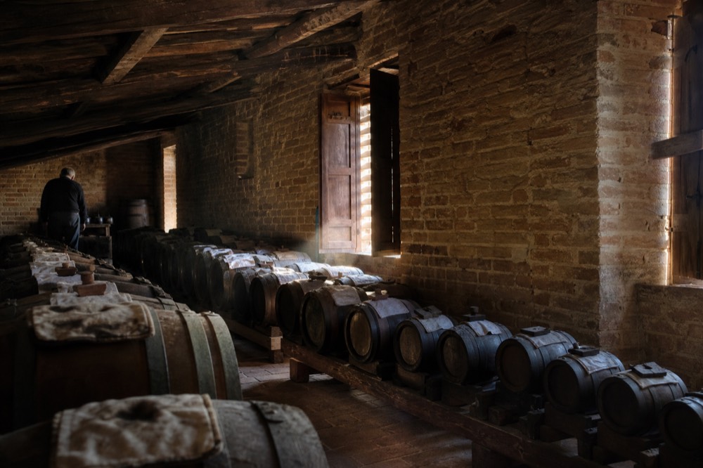 Rows of wooden ageing barrels in a dim attic vinegar loft