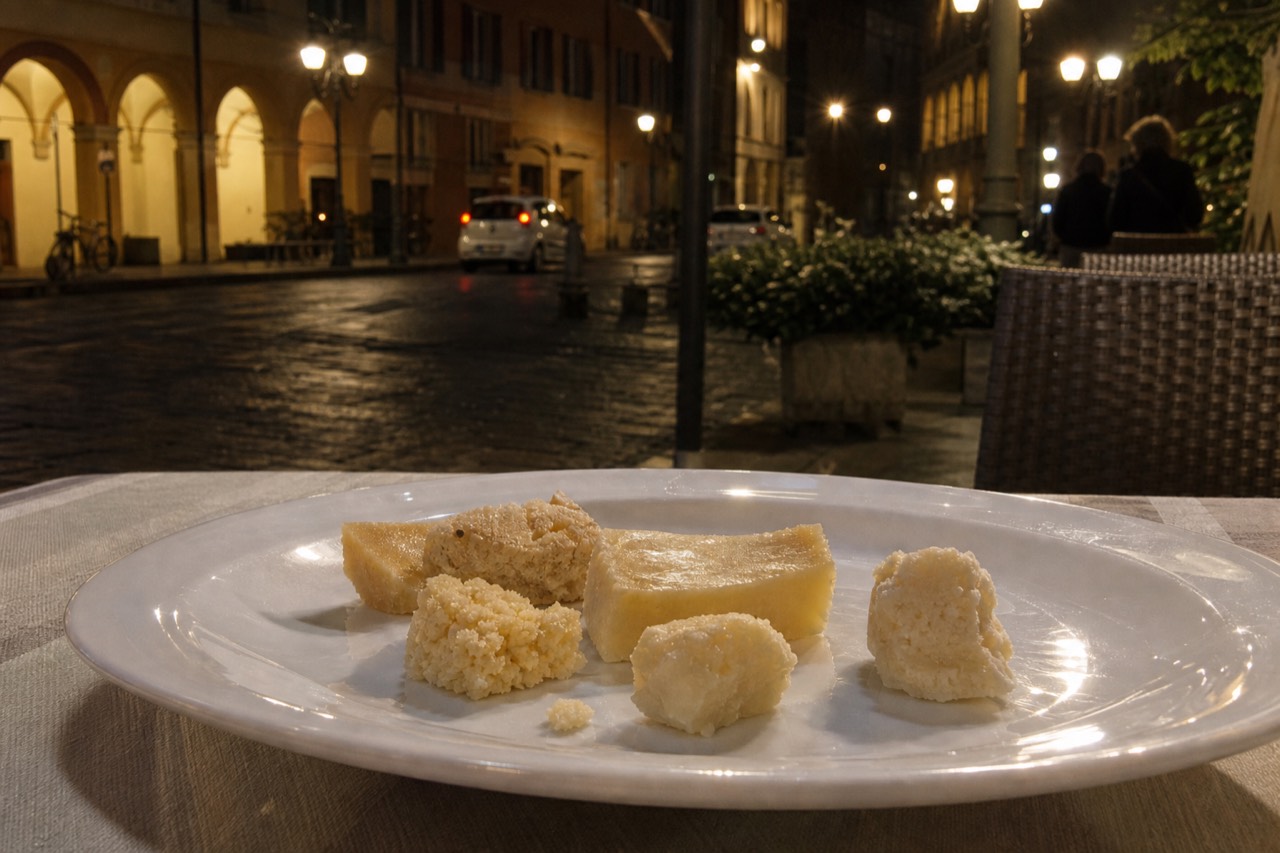 A plated fine dining dish with aged cheese in several textures on a white plate