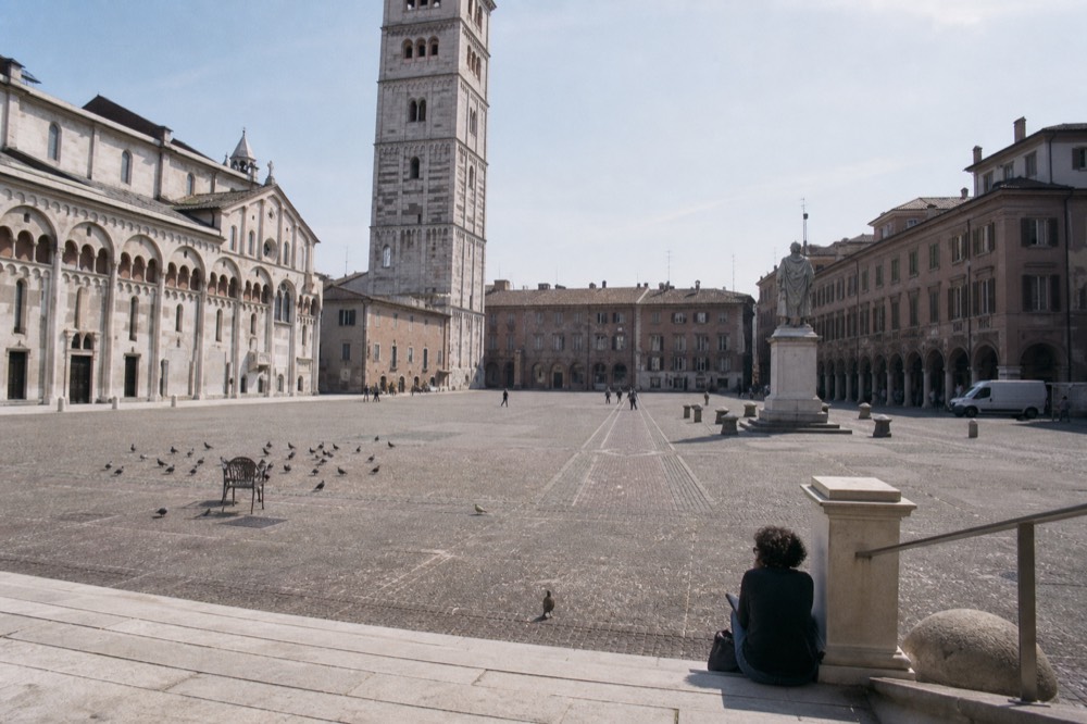 A historic Italian square with a cathedral and a tall bell tower under a clear sky