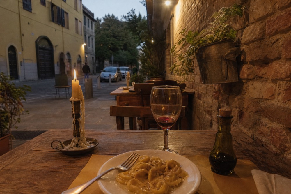 A table set with fresh pasta, a glass of red wine and a bottle of balsamic vinegar