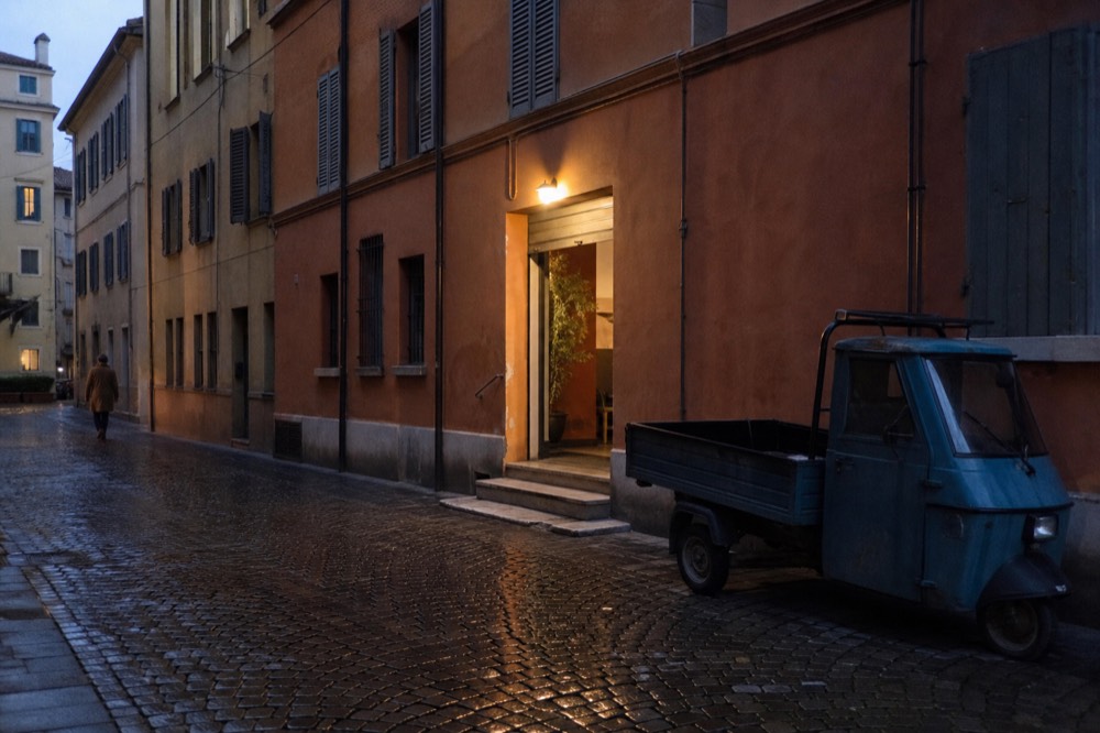 A narrow Italian street with old buildings and a small restaurant entrance
