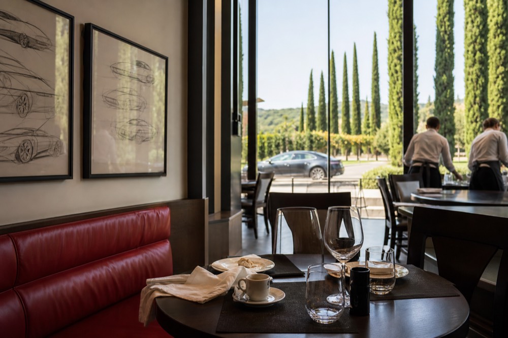 A modern dining room with red accents and car design sketches on the wall