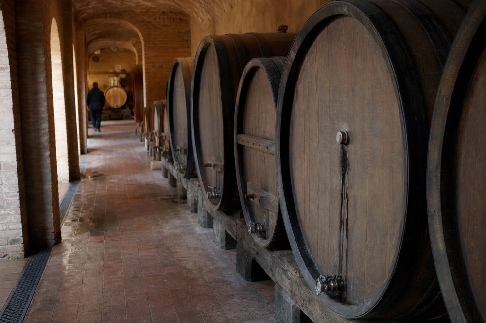 Old wine cellar with rows of large wooden casks along an arched corridor