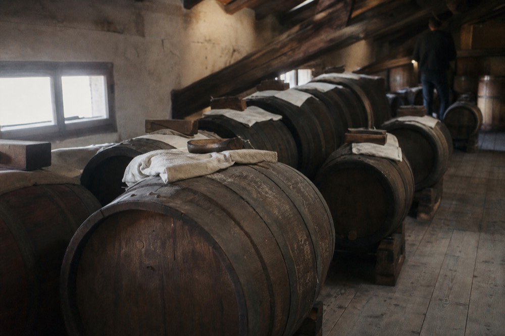 A battery of small wooden barrels of different sizes arranged in a row inside a traditional vinegar attic