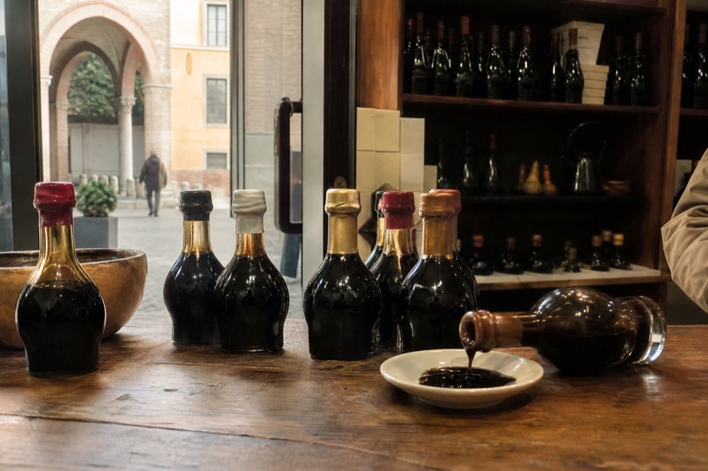 A shop counter displaying rows of small sealed balsamic vinegar bottles with wax seals