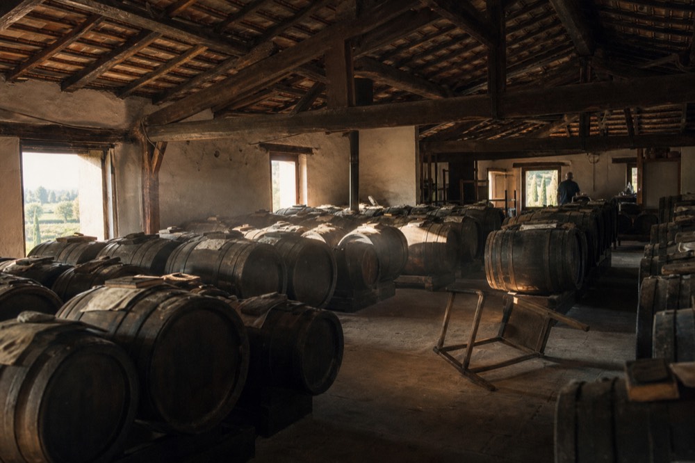 An attic vinegar loft with sunlight falling on ranks of ageing barrels under a tiled roof