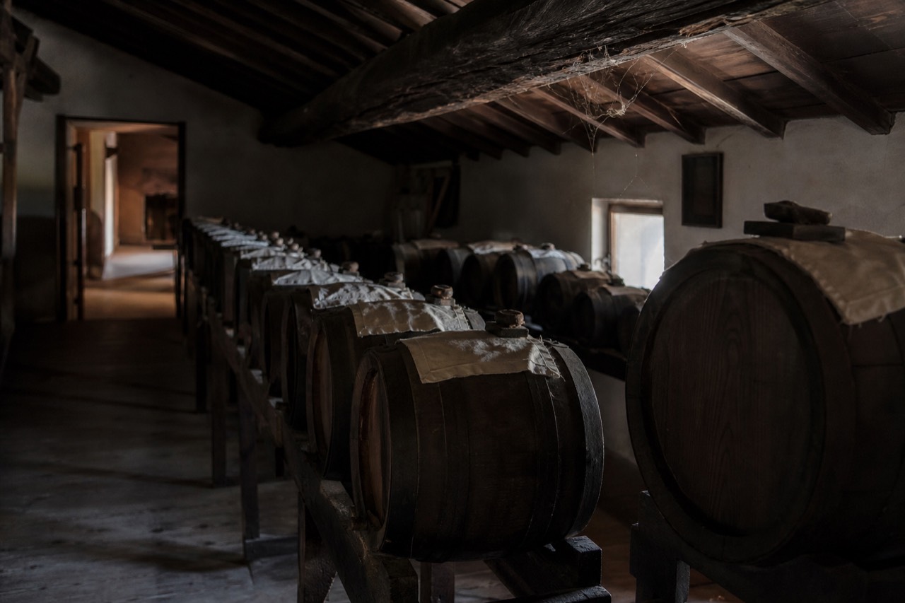A row of small wooden ageing barrels in a dim attic vinegar loft in Modena
