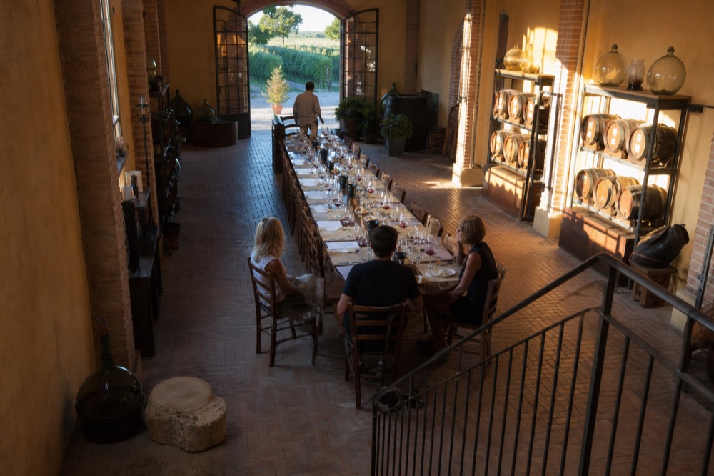 A long table set with wine glasses, bread and plates of cheese in a tasting room