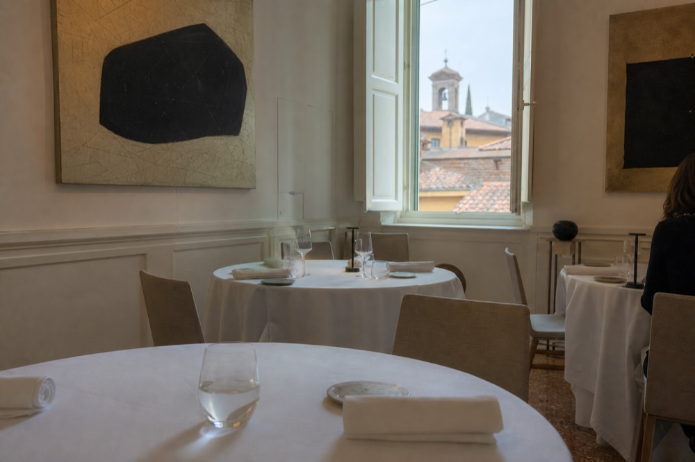 A dining room with modern artwork on white walls and set tables