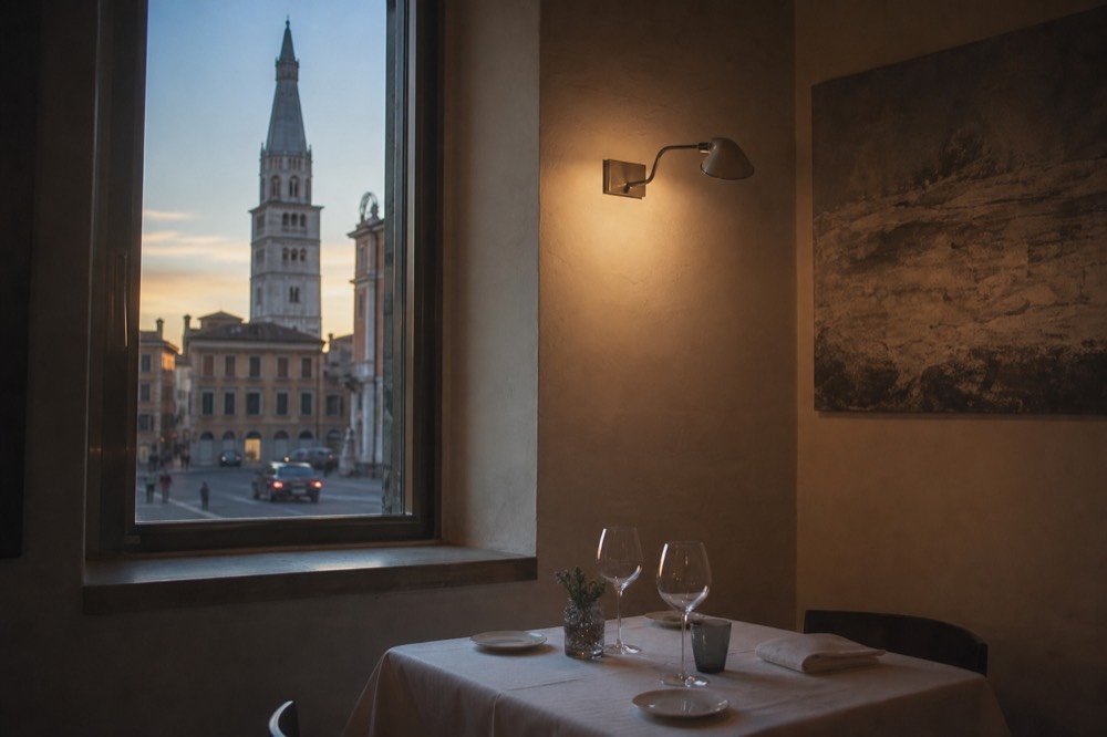 A small dining room corner with contemporary art and a table set with white linen