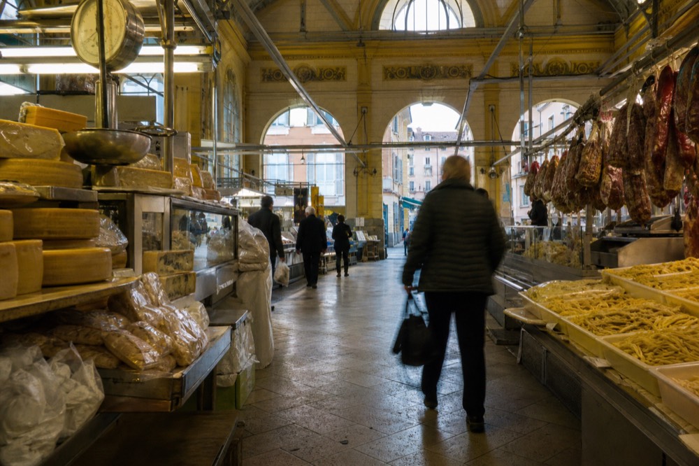 A covered market hall with stalls of cheese, cured meats and fresh pasta