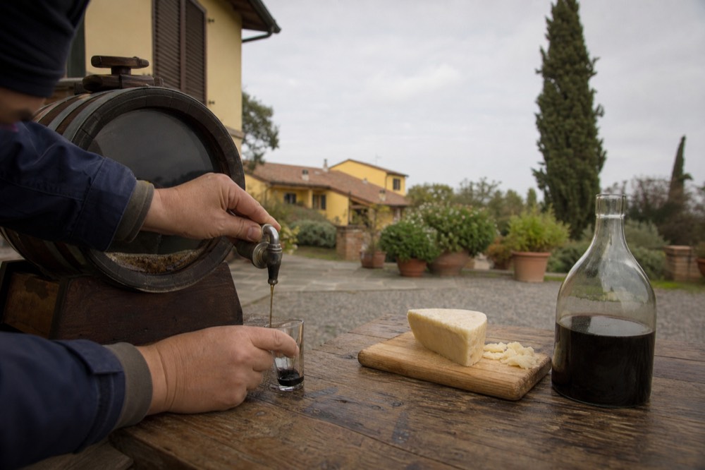 A guide pouring a small measure of dark balsamic vinegar from a glass barrel spigot