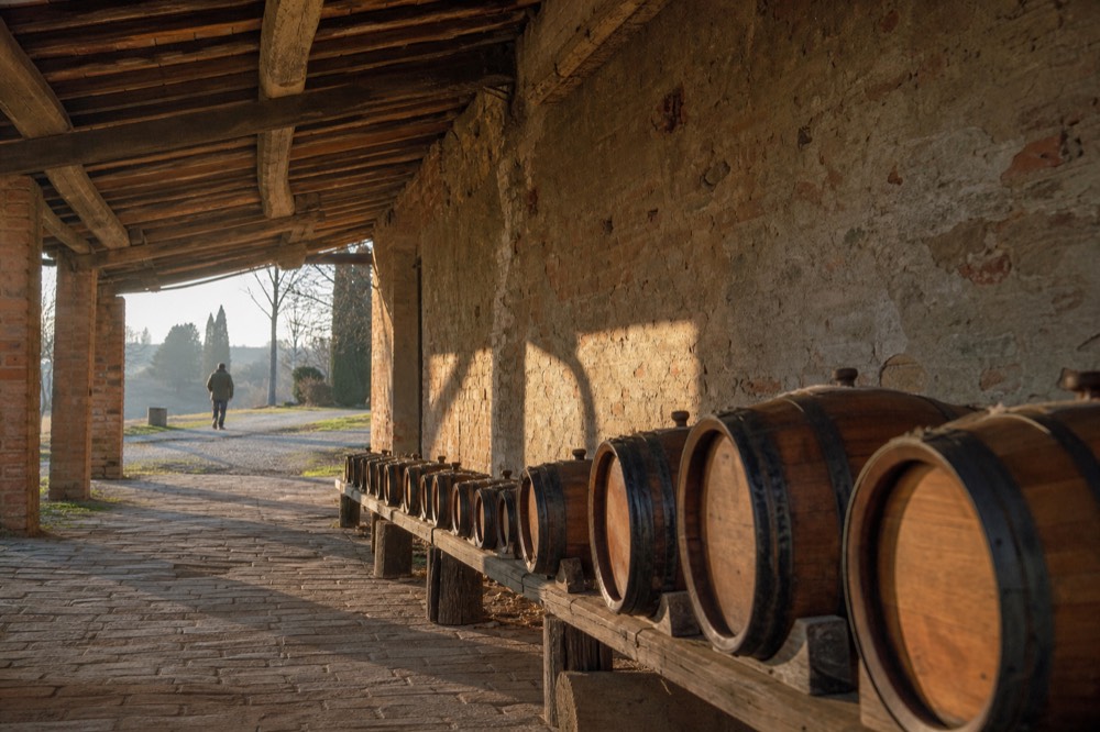 A set of wooden barrels in descending sizes lined along a brick attic wall