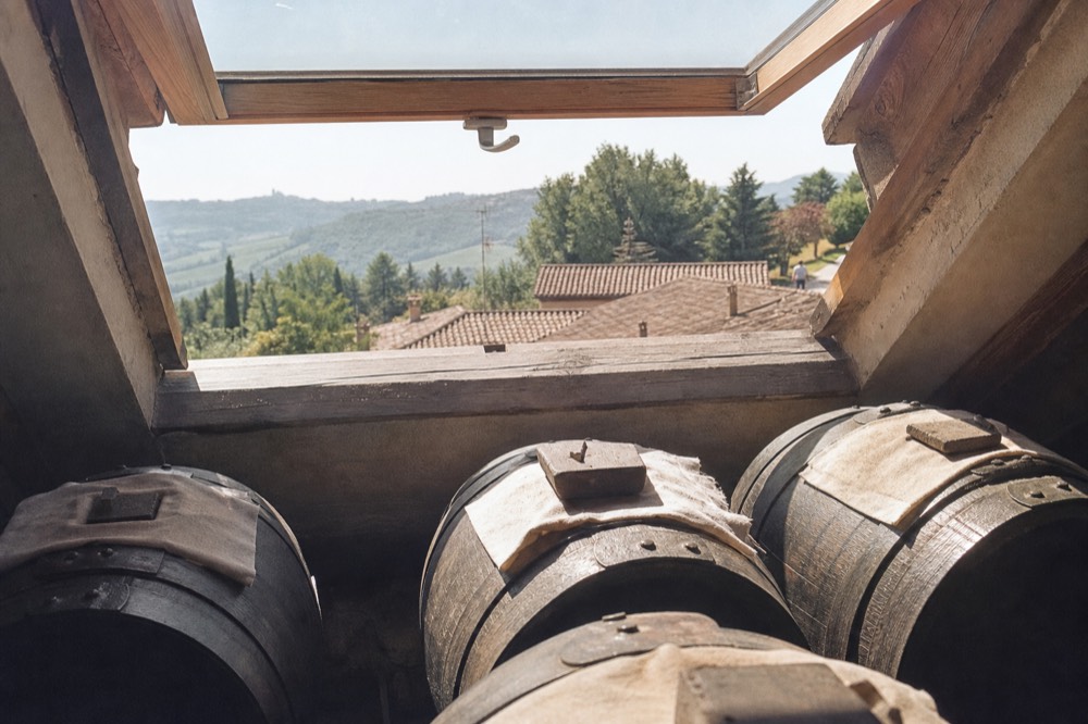 Sunlight falling through a small attic window onto dark wooden barrel tops