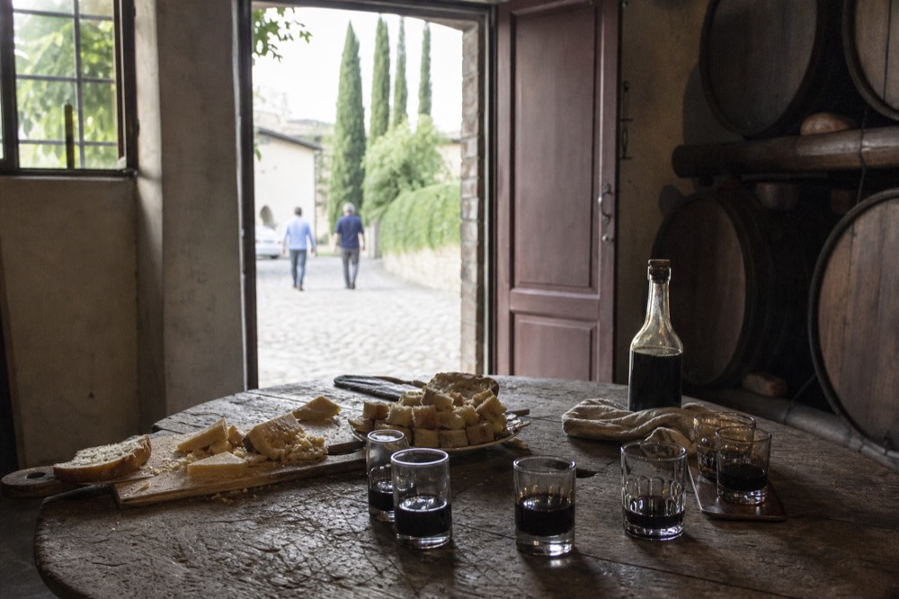 A tasting table set with small glasses of dark vinegar, bread and cheese