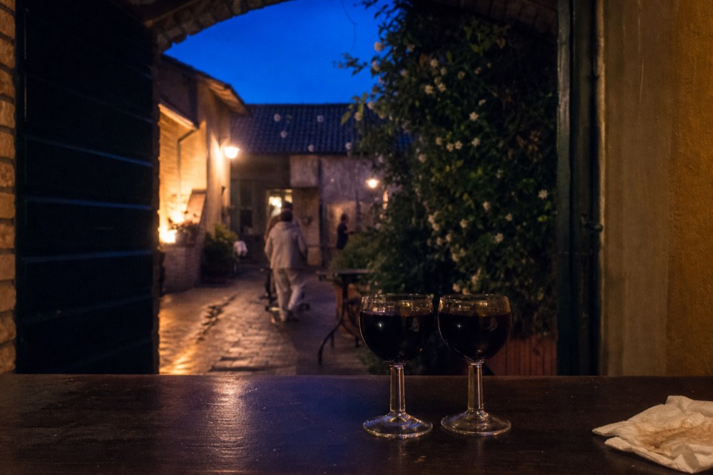 Two small glasses of dark traditional balsamic vinegar side by side on a wooden counter