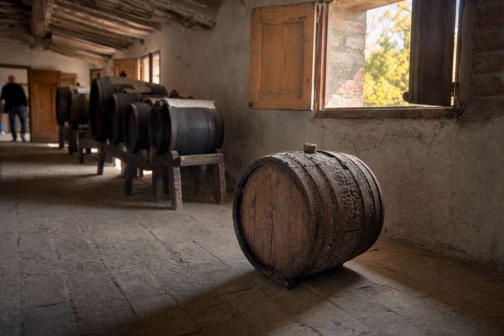 Very old small wooden barrel with weathered staves inside a traditional acetaia