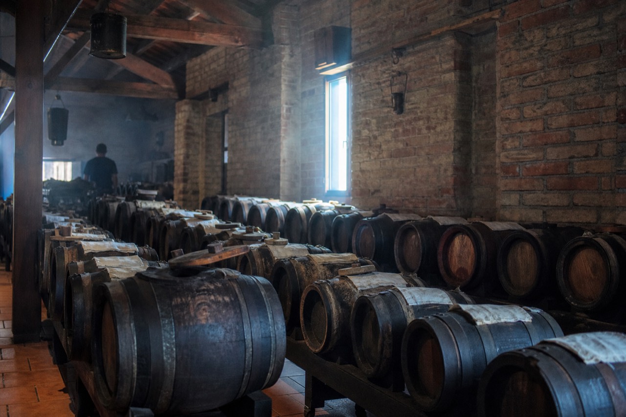 Row of small wooden ageing barrels in a Modena acetaia loft