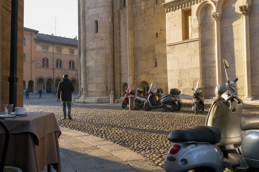A wide cobbled square lined with historic buildings in morning light