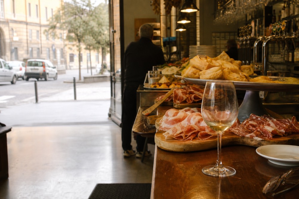 A market bar counter with small plates of cured meats and fried dough on wooden boards