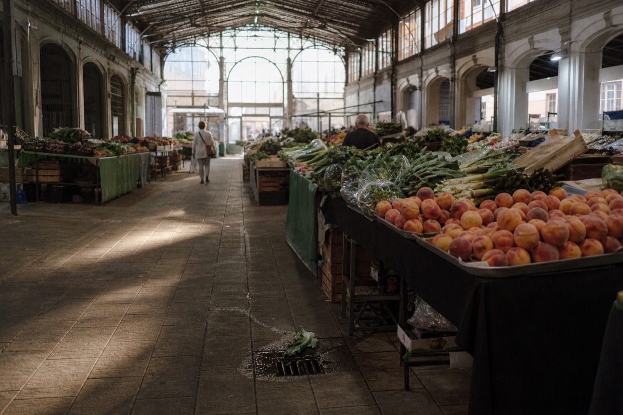 Interior of a covered market hall with produce stalls under an arched roof