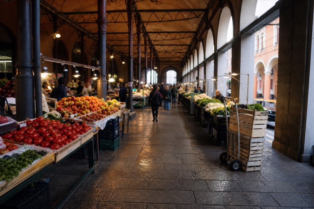 A covered market hall with fruit and vegetable stalls under arched ceilings