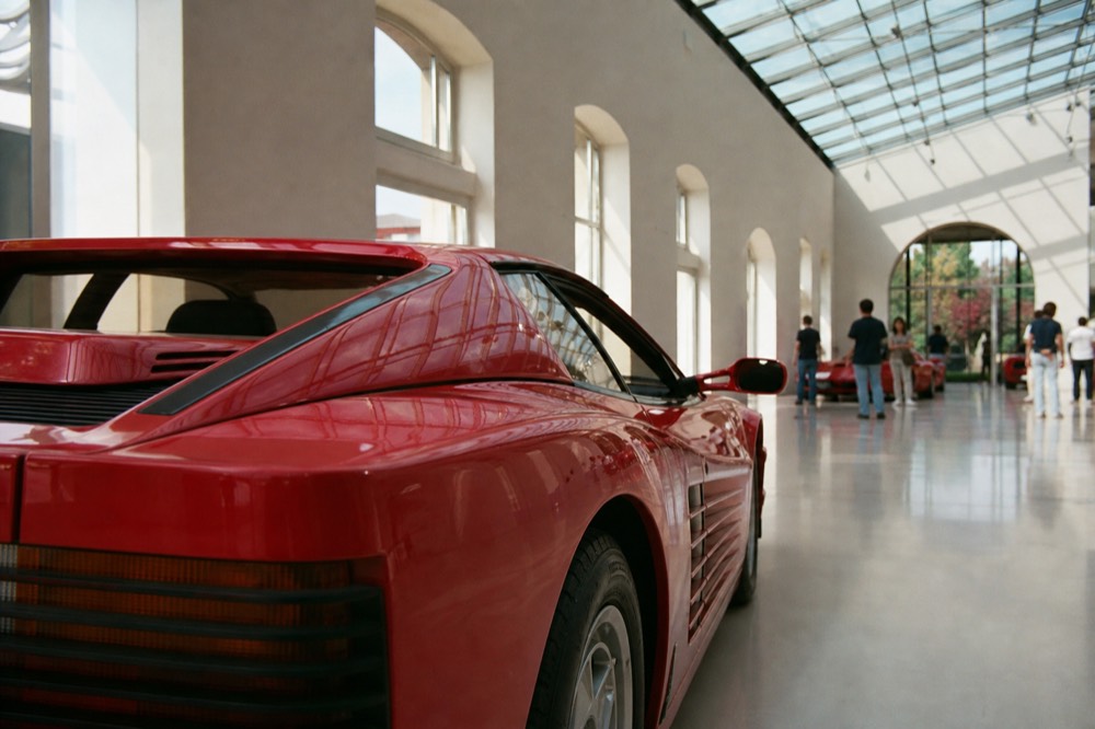 A red sports car displayed inside a bright modern museum hall