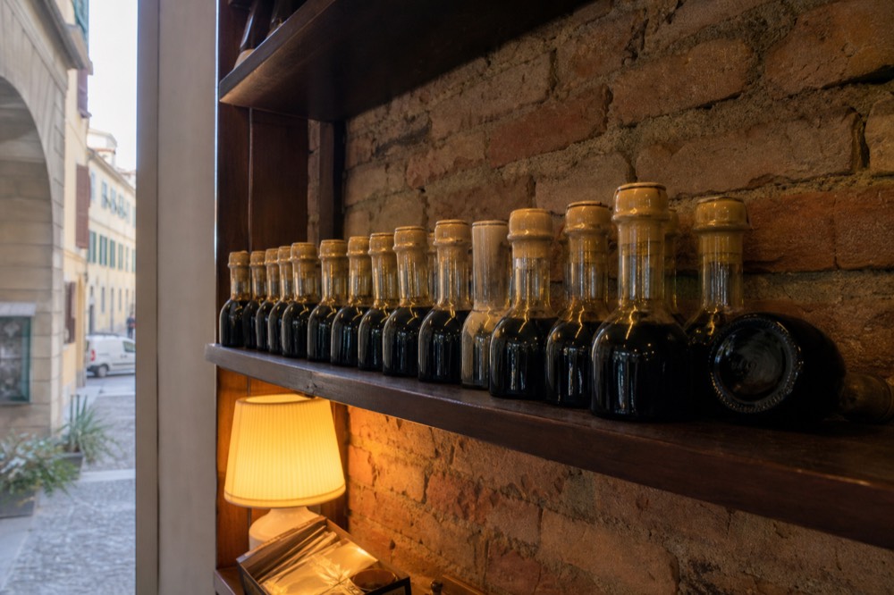 A shelf of small sealed vinegar bottles with numbered labels in a producer shop