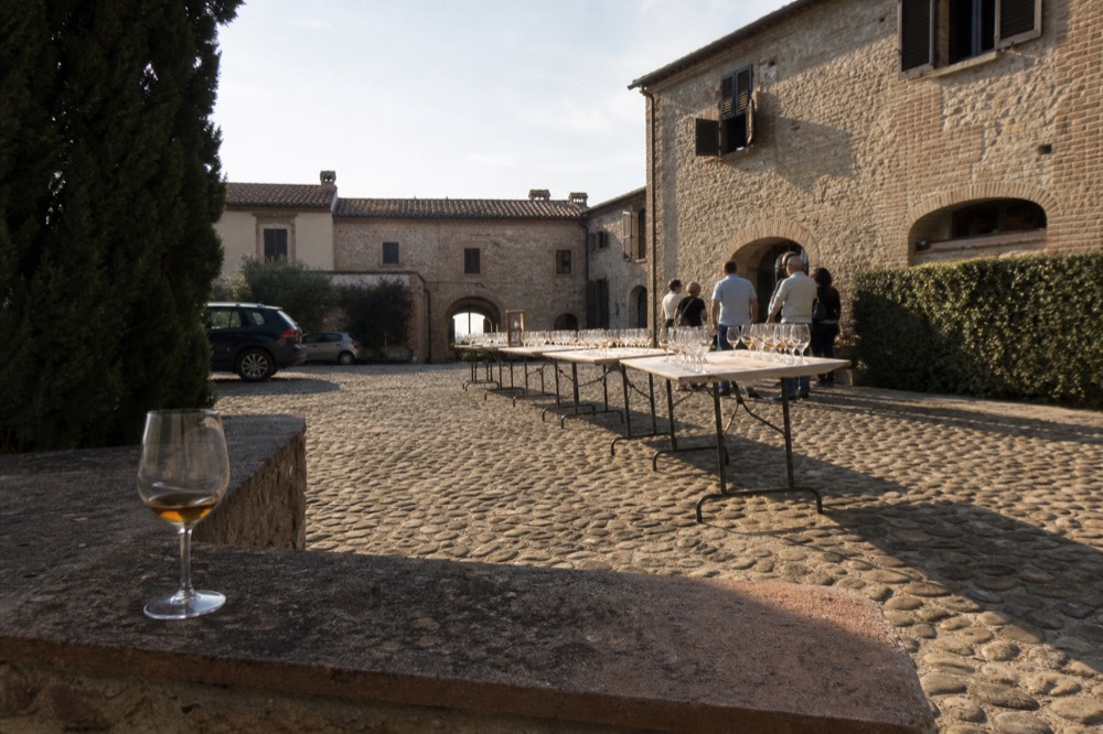 A crowded open-door producer courtyard with tasting tables set out for visitors