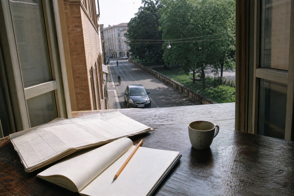 A calendar and notebook on a wooden table beside a cup of coffee