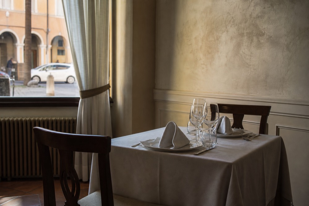An elegantly set restaurant table with white linen and glassware in soft light