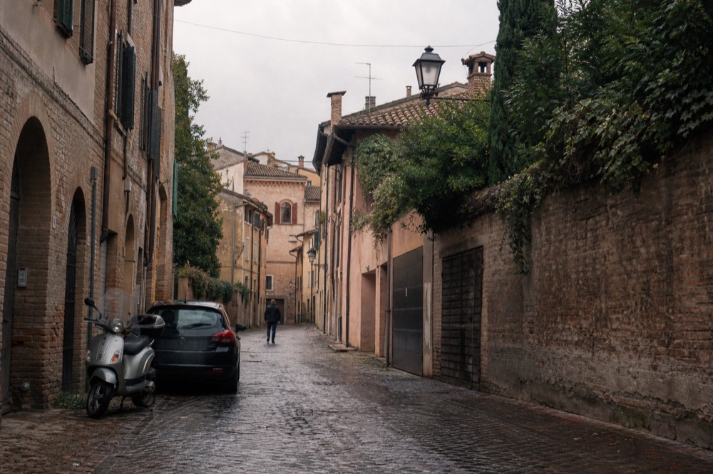 A narrow historic street in Modena with old brick facades and parked bicycles