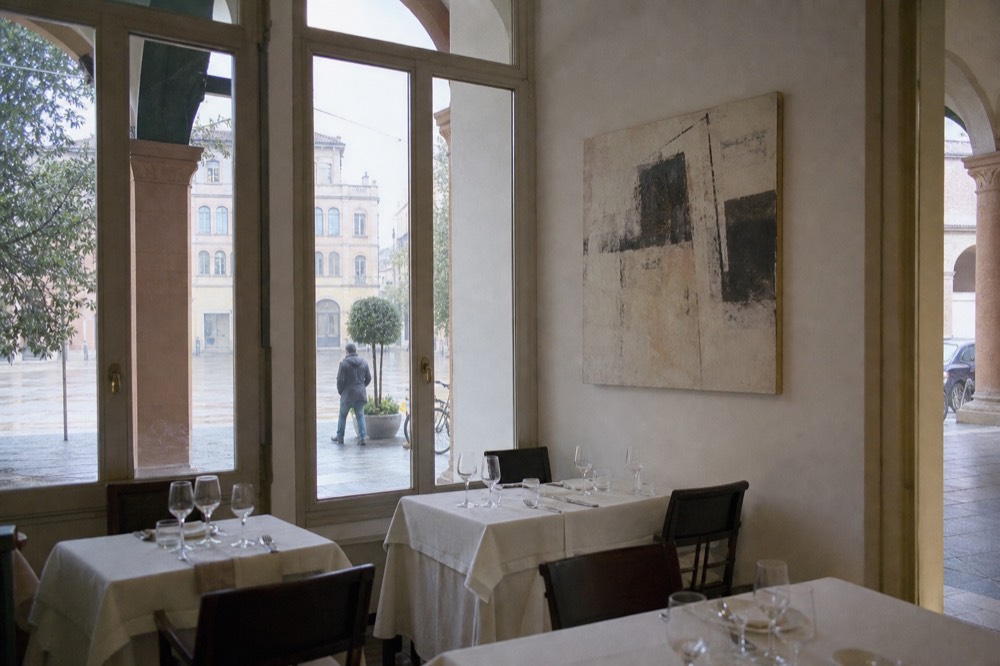 A dining room interior with modern artwork on white walls and set tables