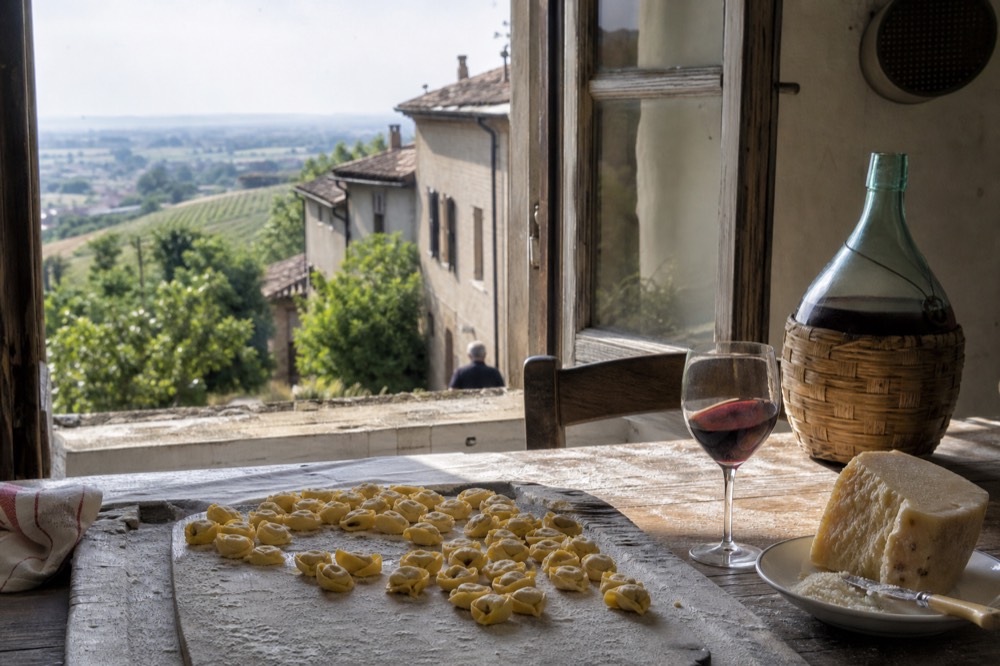 A table with fresh pasta, cheese and a glass of red wine in a rustic kitchen setting