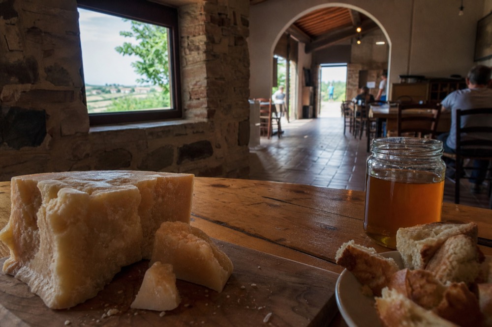 A tasting board of Parmigiano Reggiano chunks with honey and bread on a wooden table