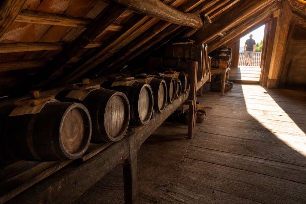 A traditional balsamic vinegar batteria with small wooden barrels of different sizes lined up in an attic