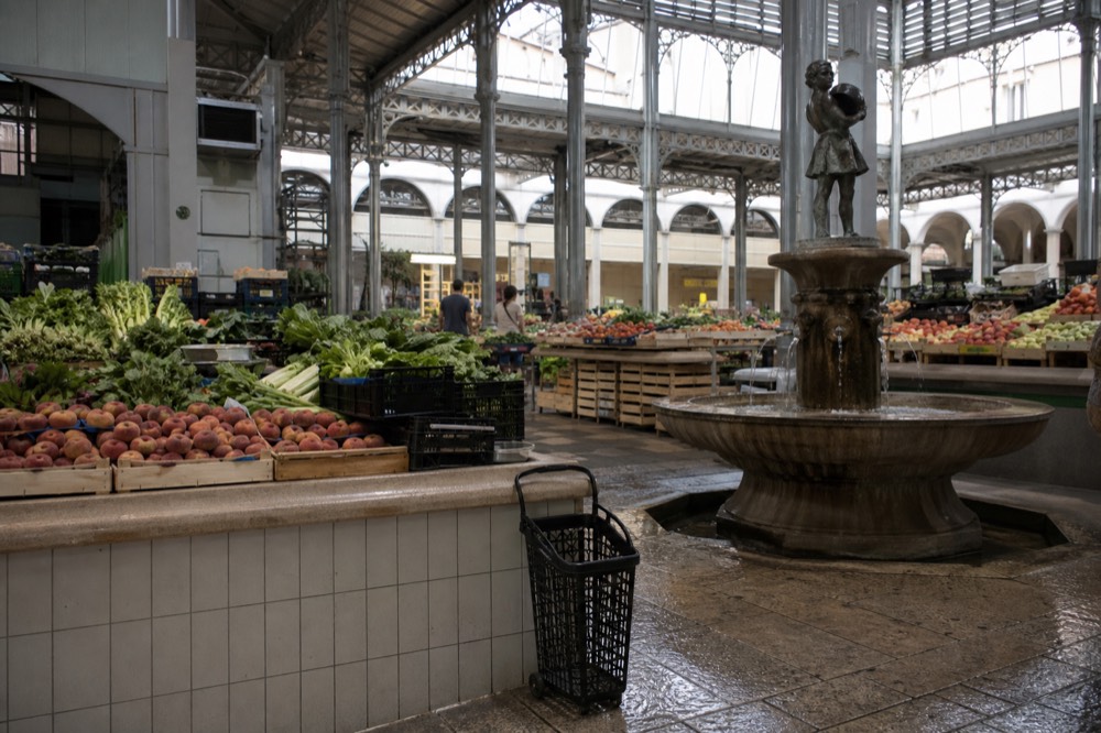 The interior of Mercato Albinelli with fruit and vegetable stalls and a central fountain